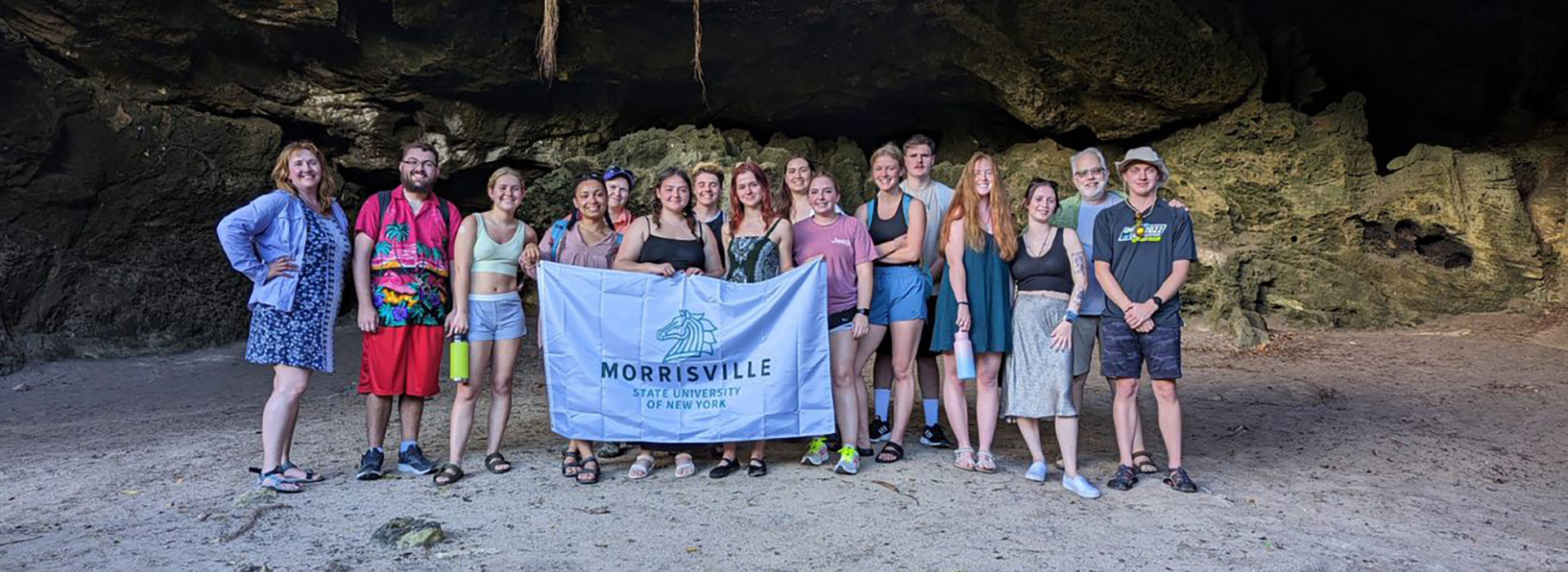Students and professors pose in the Bahamas with the SUNY Morrisville flag