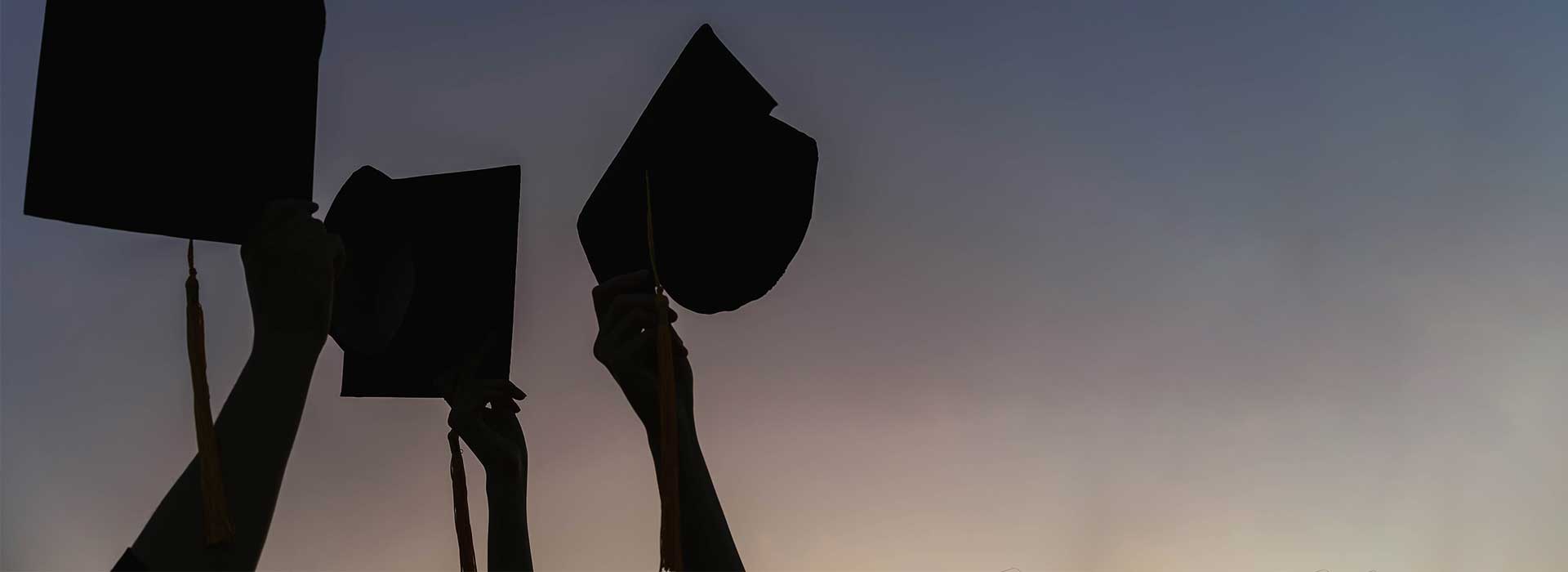 a hand raising a graduation cap into the air