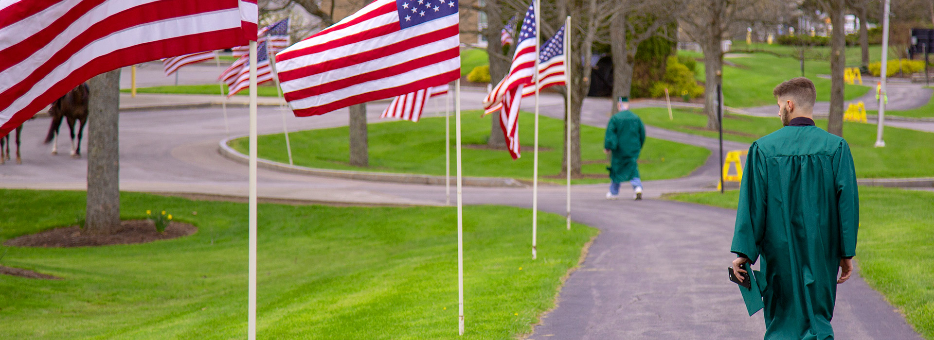 A SUNY Morrisville graduate walks around campus in his regalia