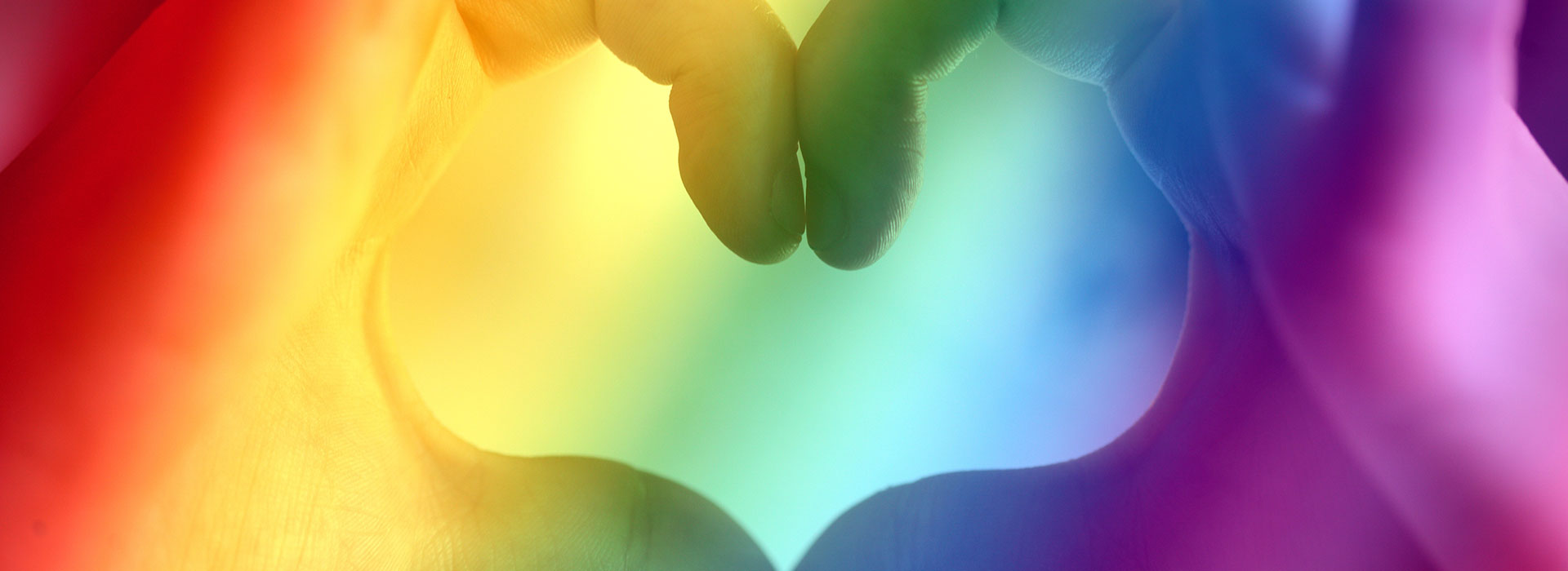 hands form a heart over a rainbow background