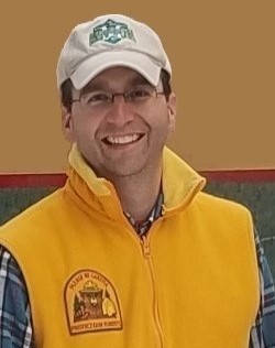 Kelly wearing a yellow vest with a Smokey Bear patch outside..