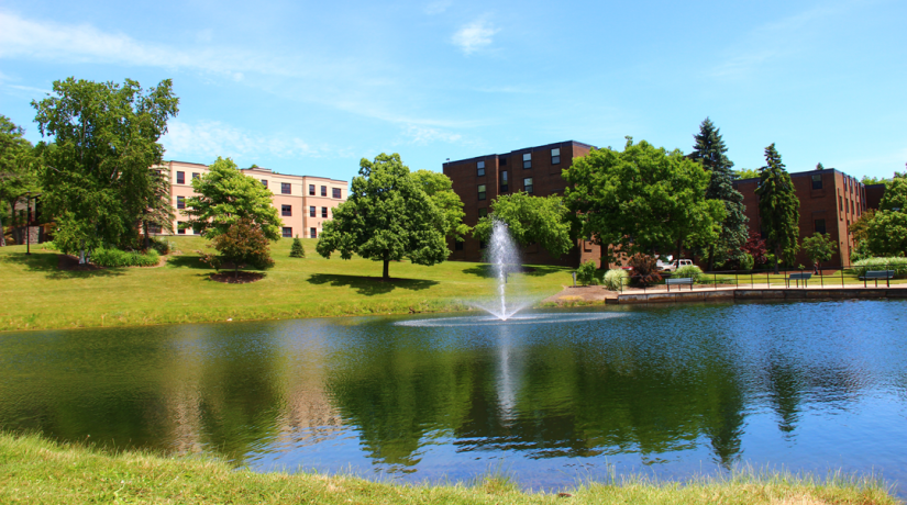 Residence halls overlooking a pond with a fountain.