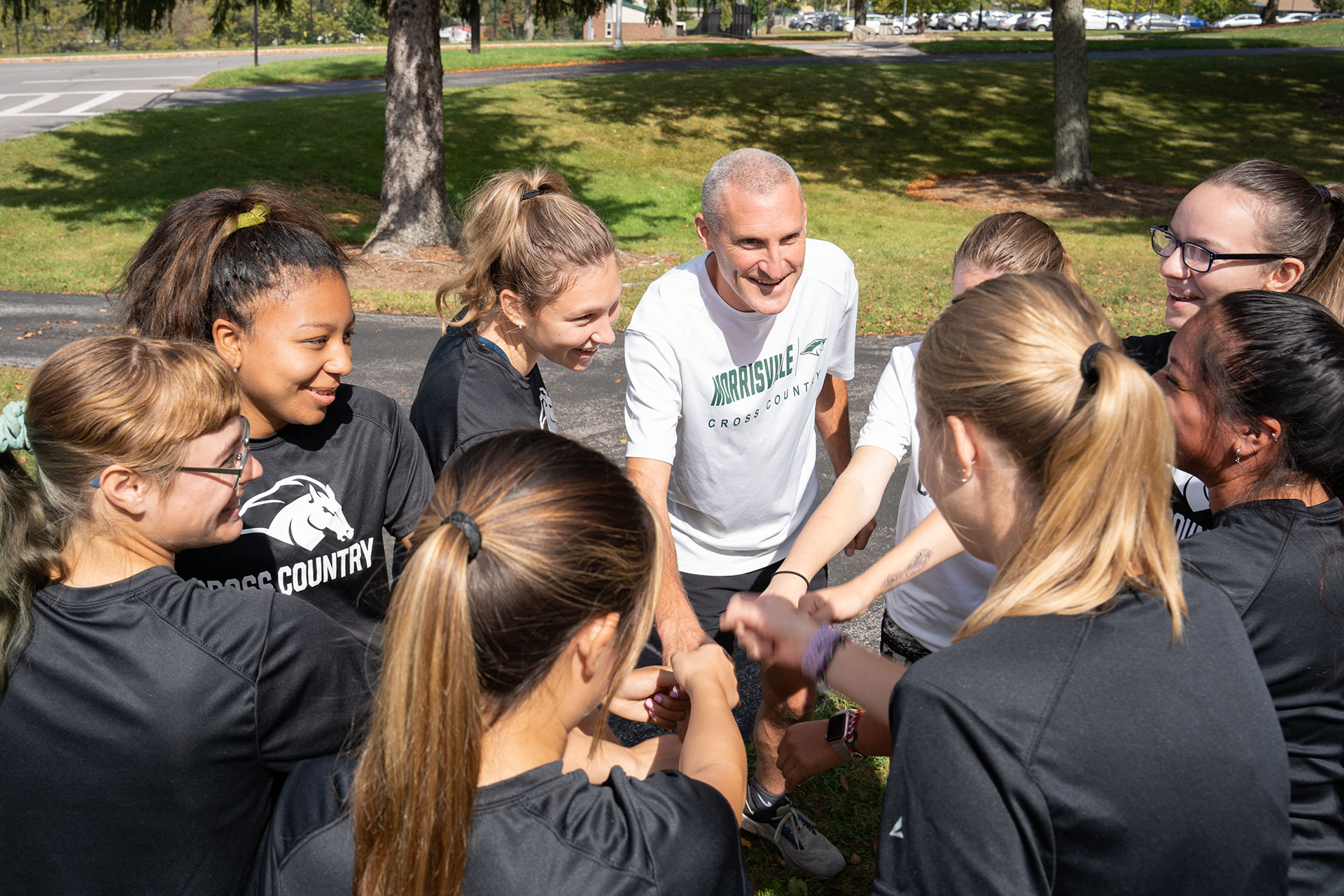 Coach Derek Powers forms a huddle with members of the women’s cross-country team.