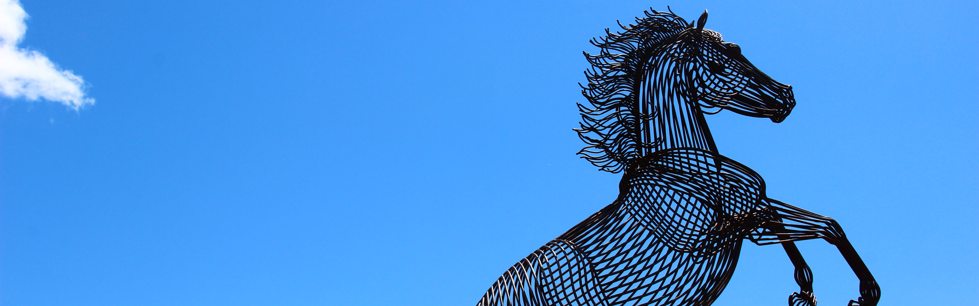 Wireframe mustang statue in front of blue sky