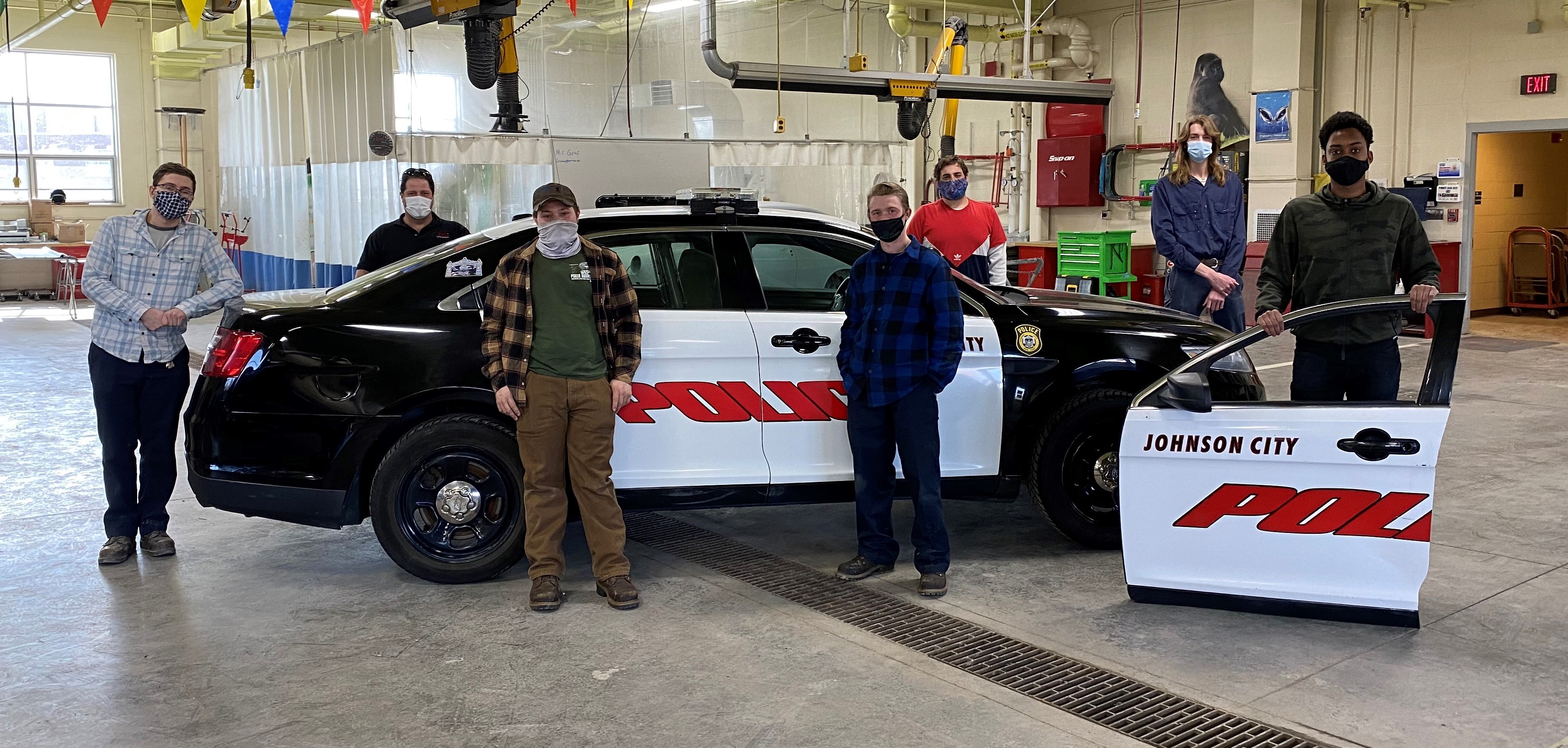 Automotive faculty and students stand in front of the completed car