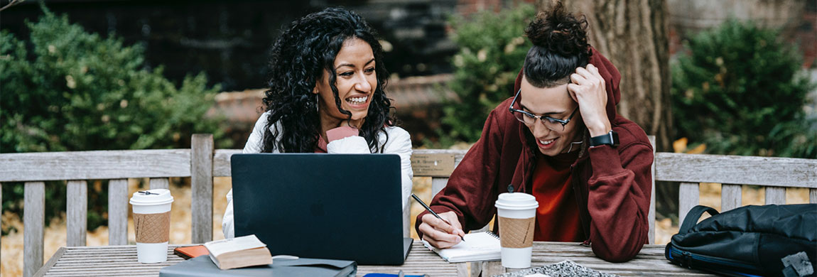 Two students study at a laptop. They look like they're having a good time.