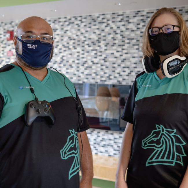 Jamal Verity (left) and Angela Rhodes, avid gamers and co-advisors for the Morrisville Competitive Gaming (MCG) student club, pose for a photo while sporting their esports team jerseys.
