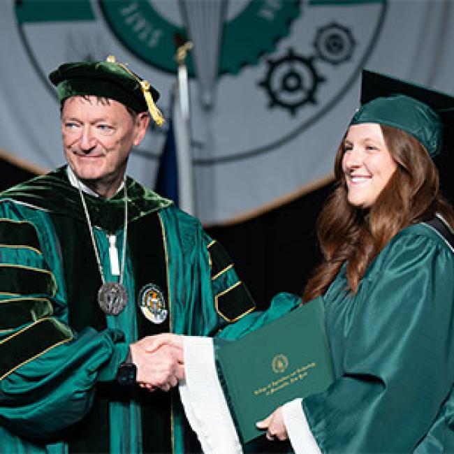 President Rogers presents a student with her diploma at Commencement.
