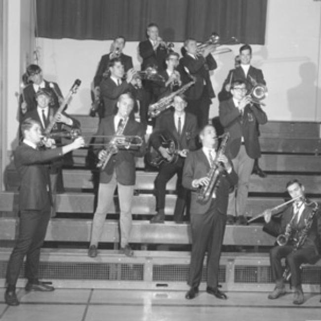 Black and white photo of a 60s band playing on bleachers 