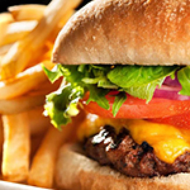 Cheeseburger on a sesame seed bun with lettuce, tomato and onion with a side of french fries