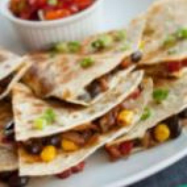 Plate of quesadillas filled with corn, beans, and scallions.