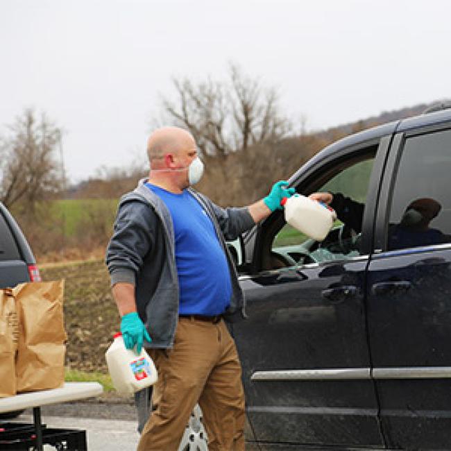 A volunteer distributes gallons of milk at the dairy drive on April 17