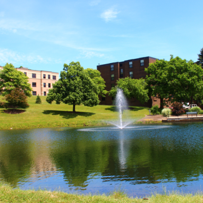 Residence halls overlooking a pond with a fountain.