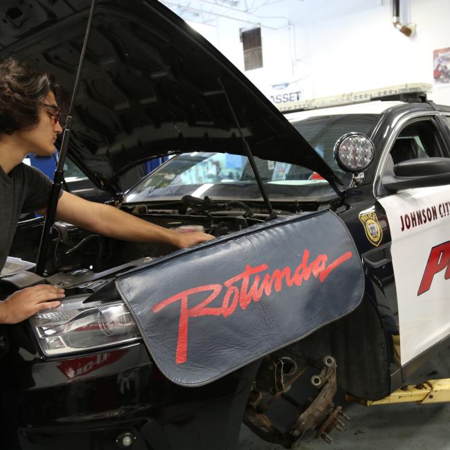 Marc McBride, an automotive business management bachelor’s degree major, from Syracuse, works on the car of a fallen police officer, which will become part of Discovery Center Story Garden, in Johnson City. 