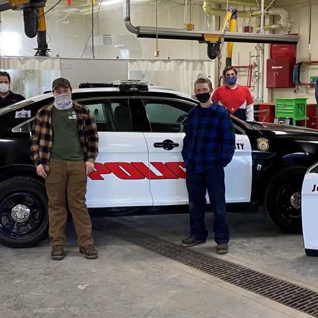 Automotive faculty and students stand in front of the completed car