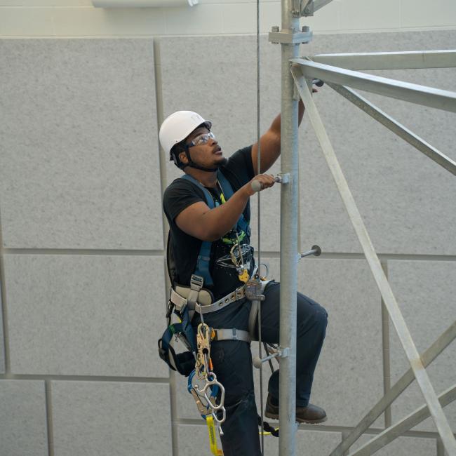 A student climbs a tower in the ACET Center