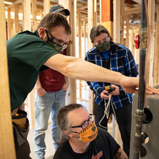 From left, Assistant Professor Ryan Quinn ’13 works with students Finneas Goodwin, Jason Crain ’21 and Eden Adler ’24 on a furnace they assembled and commissioned in a residential heating systems class.