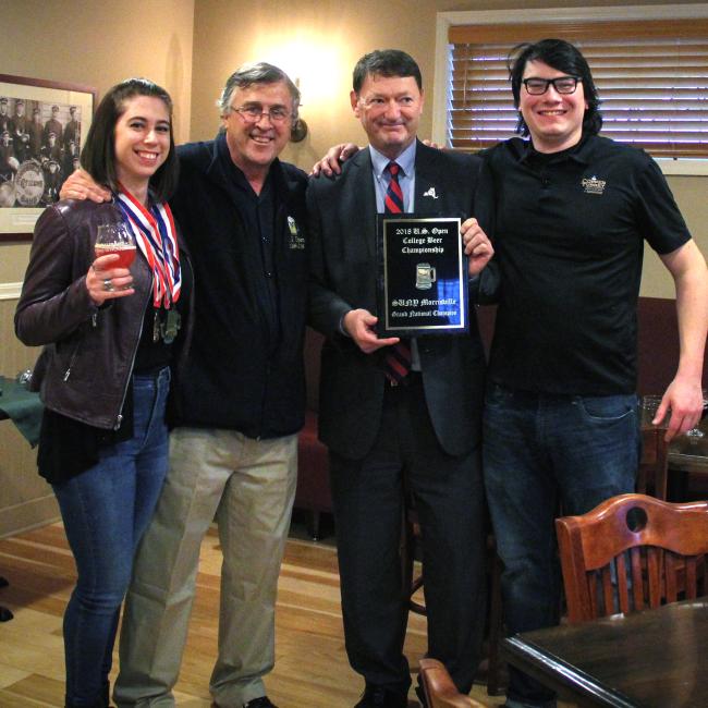 SUNY Morrisville President David Rogers (second from right), head brewer Micheal Coons (far right) and student Mary Cosenza (far left) were presented with a championship plaque by U.S. Open Beer Championships Director Dow Scoggins. Morrisville was named Grand National Champion of this year's competition (Photo credit Sarah Marcellus, MAC Associate Graphic Designer).