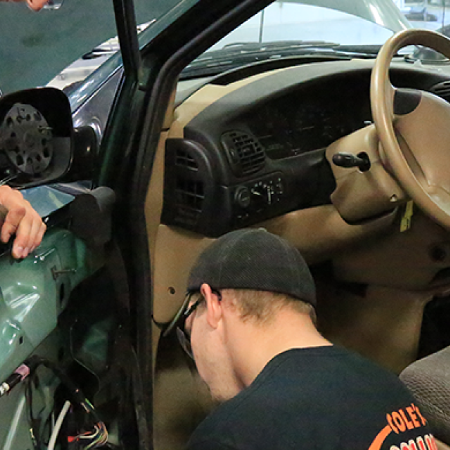 Auto body students working on a car