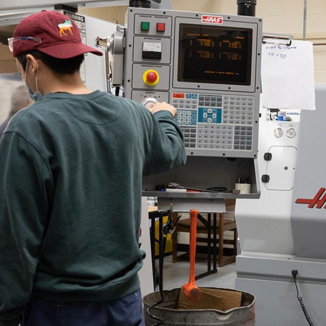 Two mechanical engineering students work with machining equipment in a lab.