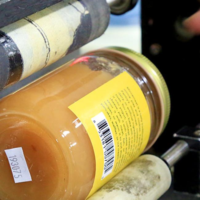 An agriculture business student uses a machine to label their product.