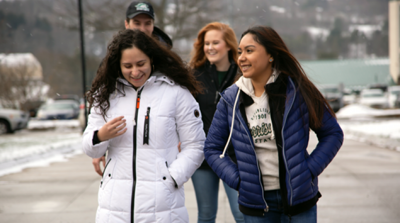 Three women and one man smile as they walk