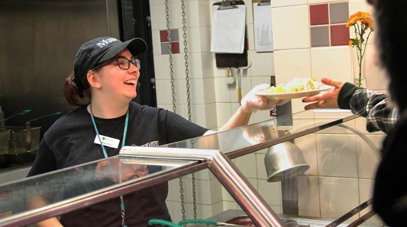 worker handing a full plate to a student