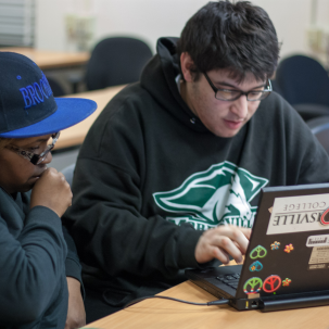 Two people focusing on the same laptop.