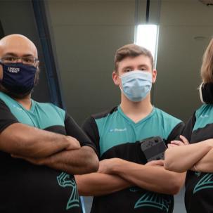 A group of SUNY Morrisville esports competitors and the advisors stand shoulder to shoulder with arms akimbo.