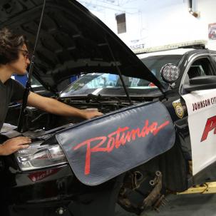 Marc McBride, an automotive business management bachelor’s degree major, from Syracuse, works on the car of a fallen police officer, which will become part of Discovery Center Story Garden, in Johnson City. 