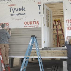 Jim Bright and Tilly Couture place siding on the small house 
