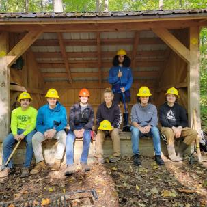 Group of people posing under wooden shelter