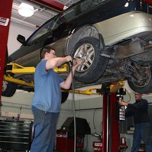 An automotive student works on a car.