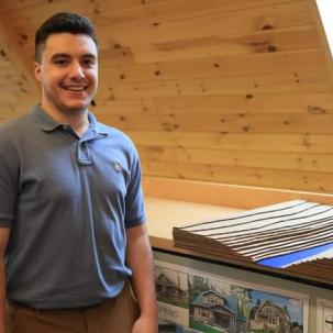 An Architectural Studies and Design student proudly poses next to a model of his design project.