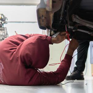 A Ford ASSET student at work underneath a car