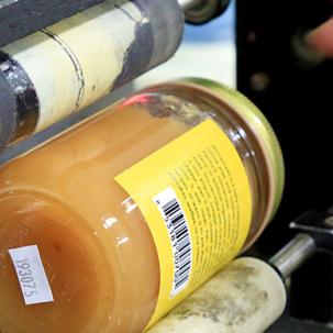 An agriculture business student uses a machine to label their product.