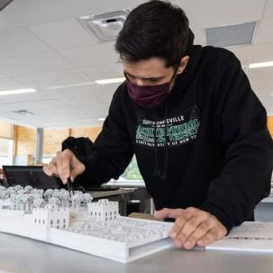 An Architectural Studies and Design student works on an architectural model of his design project.